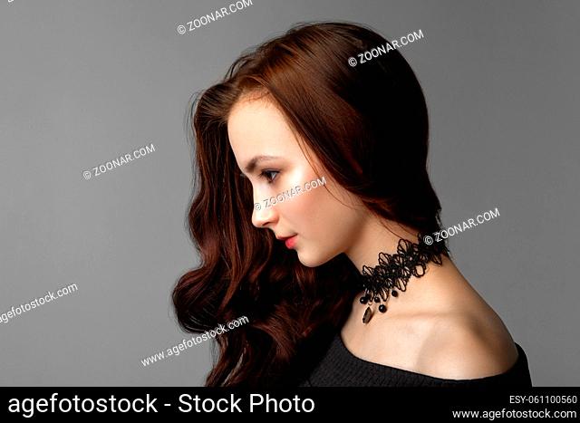Pretty woman with long brown hairs. Profile portrait of the fashion model posing at studio