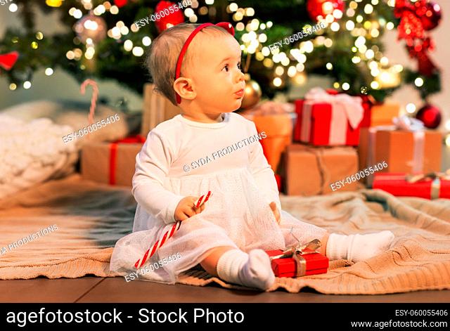 baby girl at christmas tree with gifts at home