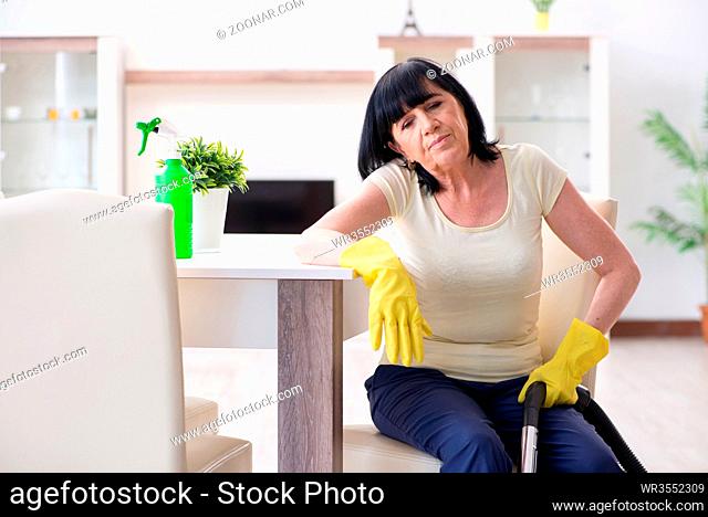 Senior old woman tired after vacuum cleaning house