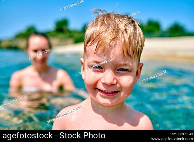 Two year old toddler boy on beach with mother