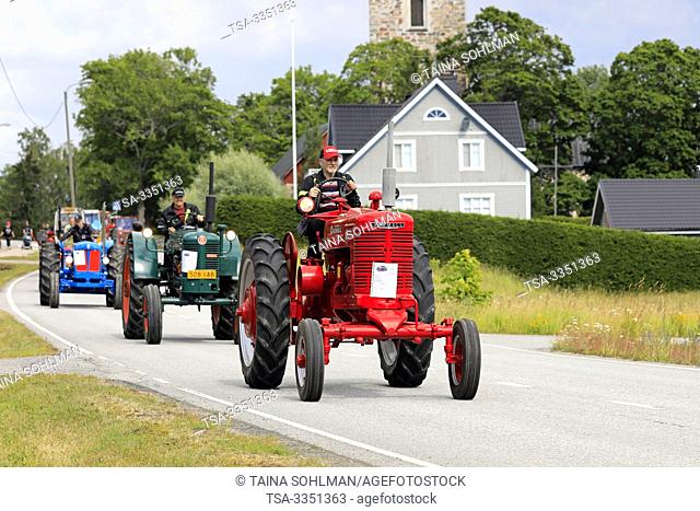 Kimito, Finland. July 6, 2019. Vintage tractors, red McCormick Farmall M first, on Kimito Traktorkavalkad, annual vintage tractor show and parade