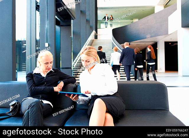 Business women sitting in lobby and surfing the net with tablet pc