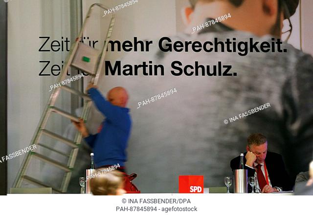 A worker carries a ladder in front of a banner reading 'Zeit fuer mehr Gerechtigkeit, Zeit fuer Martin Schulz' (lit. 'Time for more justice