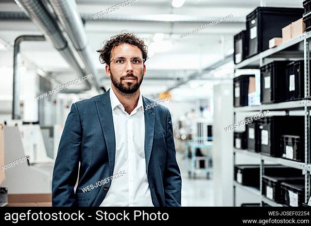 Confident businessman wearing eyeglasses while standing at industry