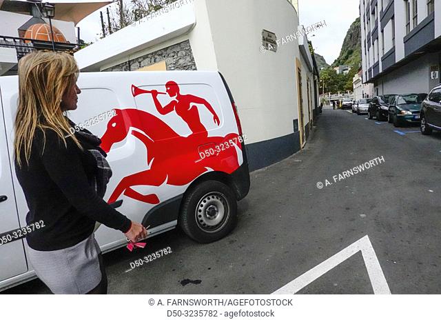 Ribeira Brava, Madeira, Portugal A woman walks by a delivery van with a bright red horse motif