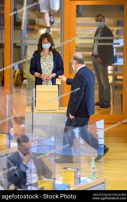 06 July 2021, Saxony-Anhalt, Magdeburg: Reiner Haseloff (r, CDU) Prime Minister of Saxony-Anhalt, goes to the ballot box with his ballot paper