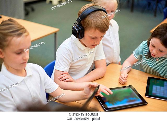 Schoolboys and girls looking at digital tablets in class at primary school