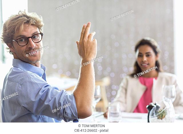 Man gesturing for service at restaurant table