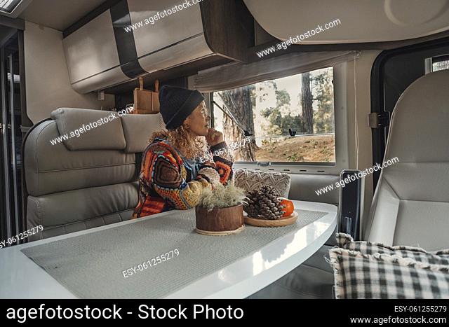Travel independent woman lifestyle looking outside the window camper van at the nature forest outdoors. Serene female people smile and enjoy alternative home...