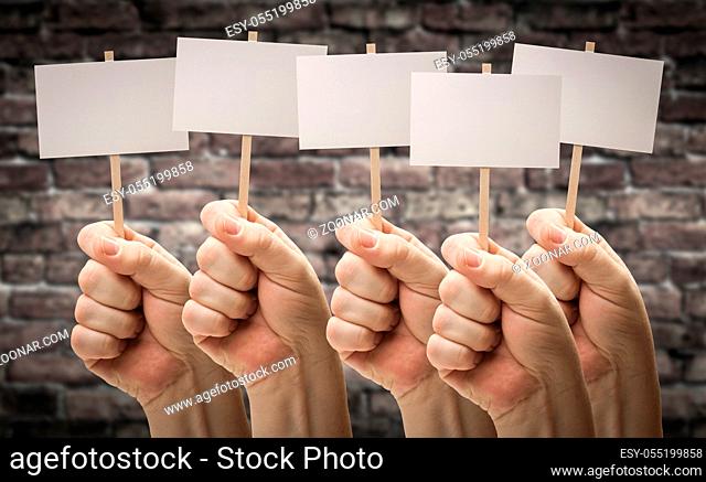 Five Male Hands Holding Blank Signs Against Aged Brick Wall
