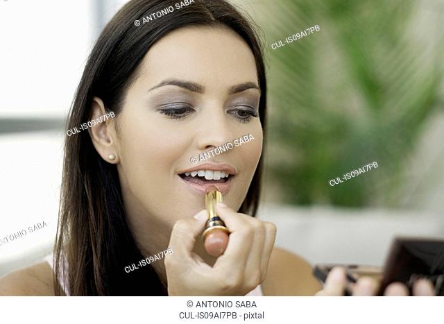 Close up of young woman applying lipstick