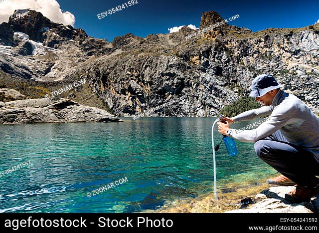mountain climber pumping and filtering drinking water from a lake in the Andes of Peru during a climbing expedition