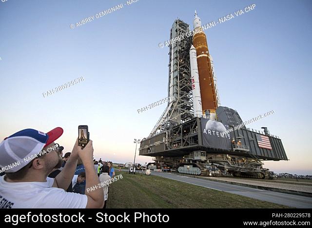 Invited guests and NASA employees take photos as NASA’s Space Launch System (SLS) rocket with the Orion spacecraft aboard is rolled out of High Bay 3 of the...
