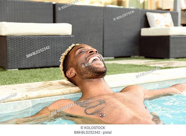 Smiling Black man relaxing in swimming pool
