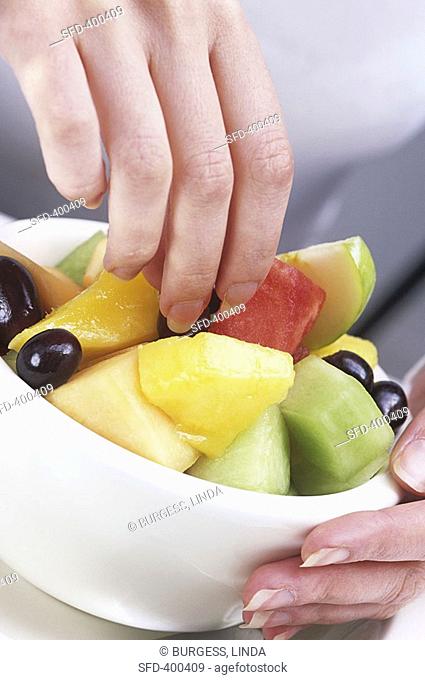 Hands with a bowl of fruit salad