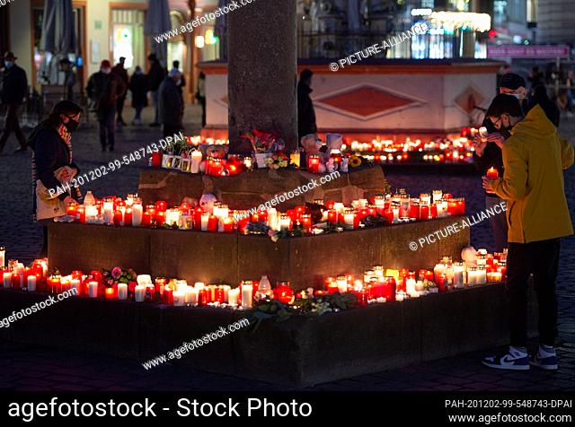 02 December 2020, Rhineland-Palatinate, Trier: In the evening, people place candles at the market cross for the victims of a rampage