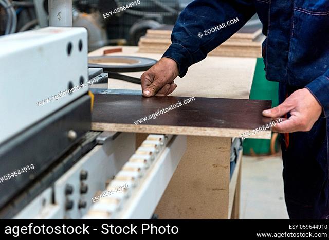 Furniture production or craft concept: worker making the wood surface of furniture part with special machine