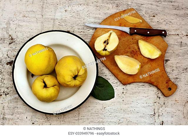 Rural still life ripe yellow quince fruits on the plate and cut fruit on plate with knife