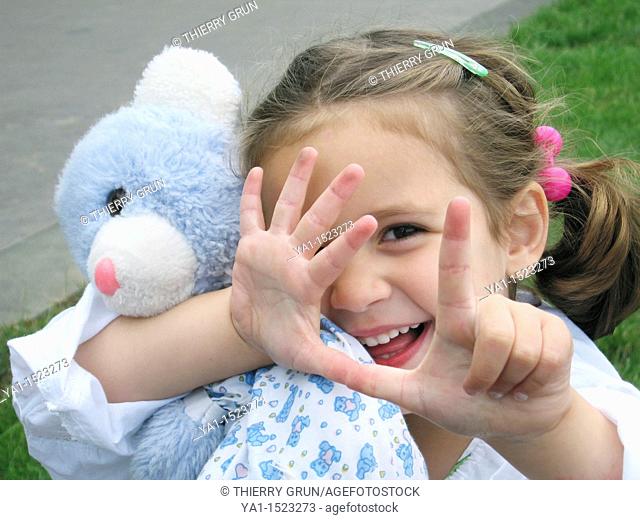 Young girl hugging her teddy bear and counting with fingers
