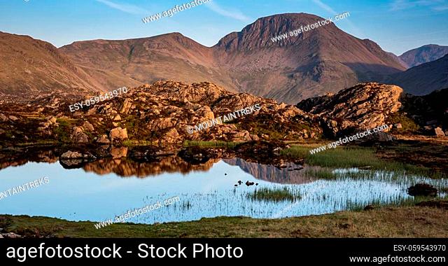 The golden evening light on the lakeland mountain of Great Gable reflecting in Innominate Tarn