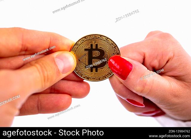 Virtual cryptocurrency money Bitcoin golden coin in the hands of a woman with red nail polish and a man. The future of money