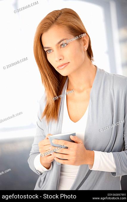 Dreamy young woman posing with coffee mug handheld