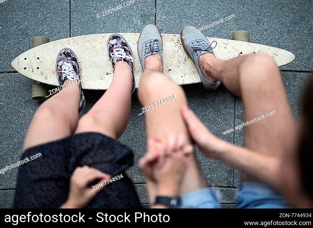 Feet couple of teenagers in sneakers standing on longboard closeup. The top point of shooting