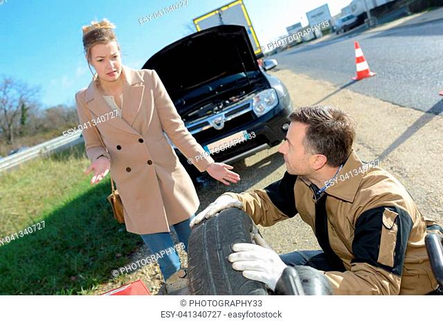 Man repairing woman's puncture beside the road