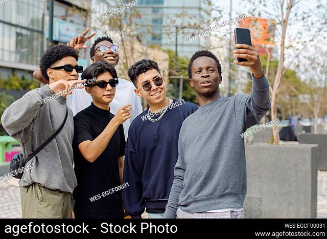 Man taking selfie with friends making peace signs