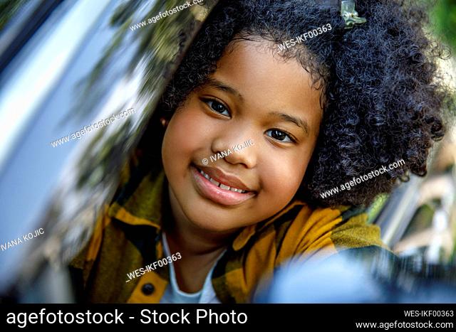 Smiling girl with curly hair in car