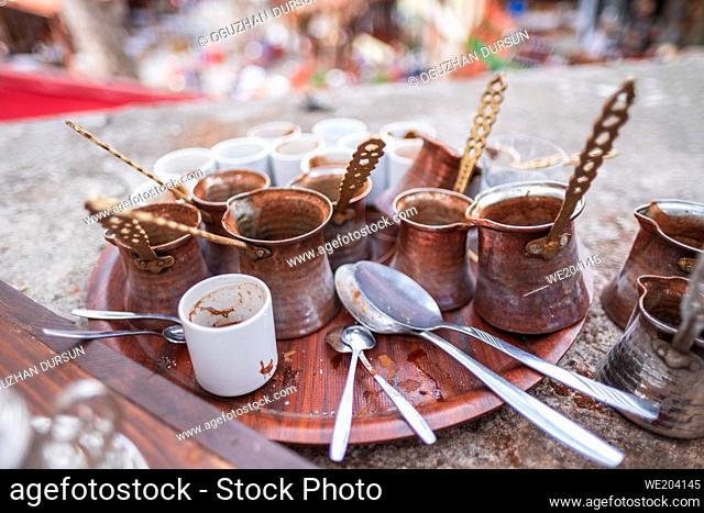a lot of copper coffee pots for turkish coffee and empty dirty coffee cups on a plastic tray in Turkey