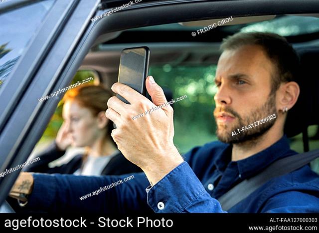 Young man using smart phone while driving a car
