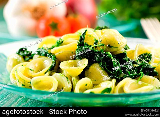 Italian Regional dish with pasta and turnip tops on green glass table