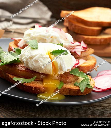 sandwich on toasted white slice of bread with poached eggs, green leaves of arugula and radish, morning breakfast