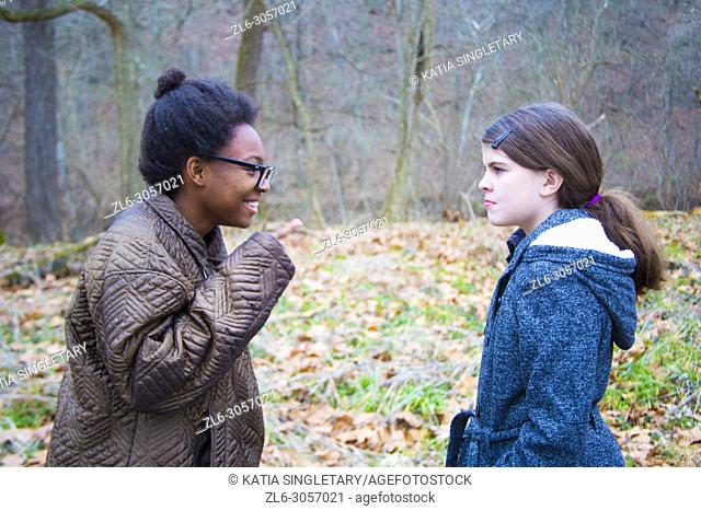 Two teens/ Pre-teens arguing. One African American teen girl, yelling and correcting her caucasian friend/sister. She is bossing her around