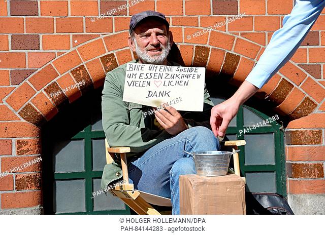 57-year-old Erwin asks nicely for a donation and receives change from a passerby in downtown Hanover,  Germany, 15 September 2016