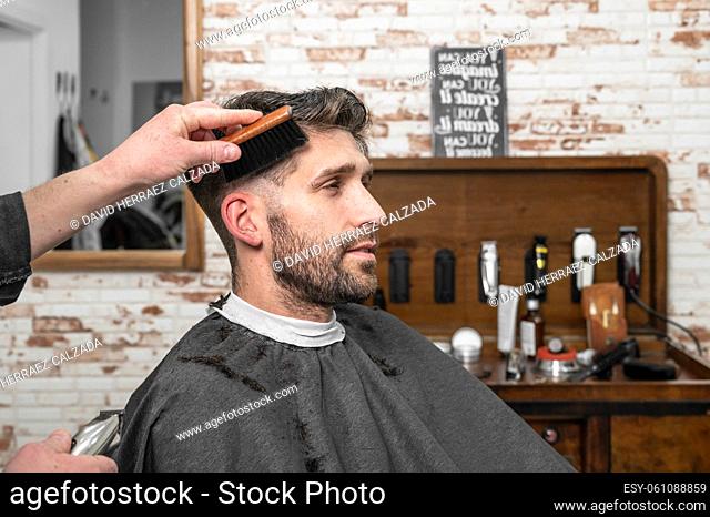 Shot of a barber using a brush on his client's beard . High quality photography