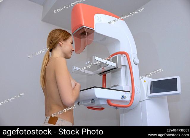 Side view of young woman getting mammogram test during breast cancer awareness program at the imaging diagnostic center