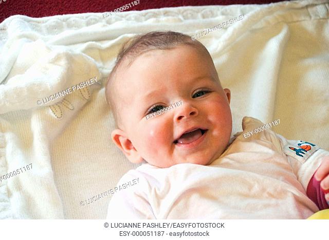 3 month old baby lying on her back, laughing into camera