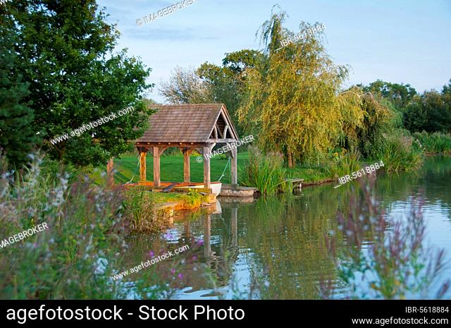View of the boathouse at the fishpond at sunset, Little Budworth, Tarporley, Cheshire, England, United Kingdom, Europe