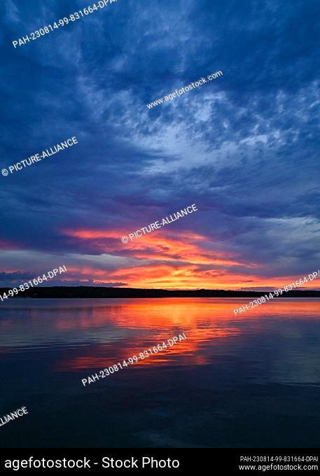 13 August 2023, Brandenburg, Bad Saarow: The sunset over the Scharmützelsee shines colorfully. The body of water in the Storkower Land region