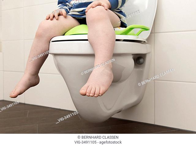 GERMANY, BARNSTEDT, 20.12.2012, 2 year old boy with childrens seat on a toilet. - Barnstedt, Germany, 20/12/2012