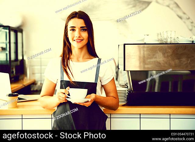 Coffee Business Concept - Caucasian female serving coffee while standing in coffee shop. Focus on female hands placing a cup of coffee