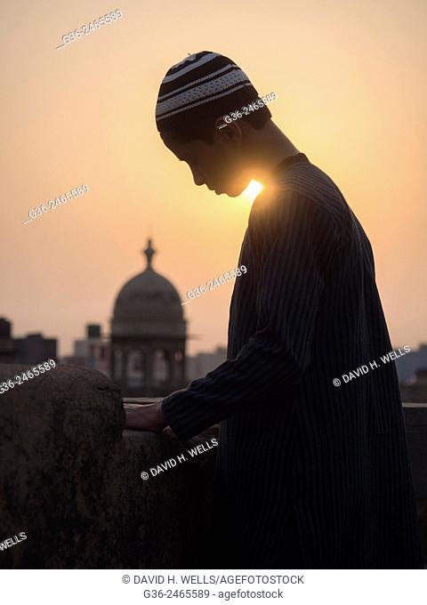 Man on roof / building terrace and Minarets at sunset, New Delhi, India