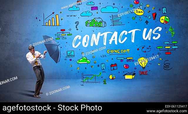 Determined businessman hiding behind umbrella with CONTACT US inscription, new business concept