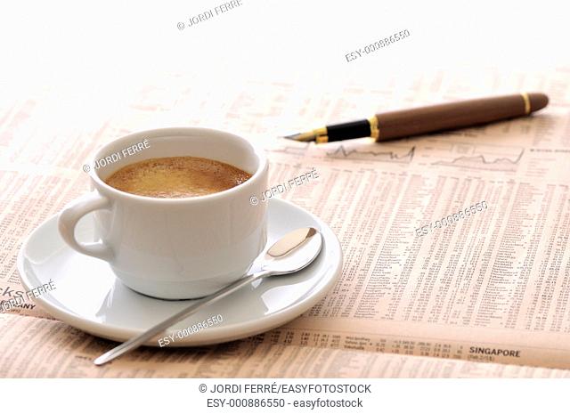 Espresso coffee and stylographic pen over a newspaper