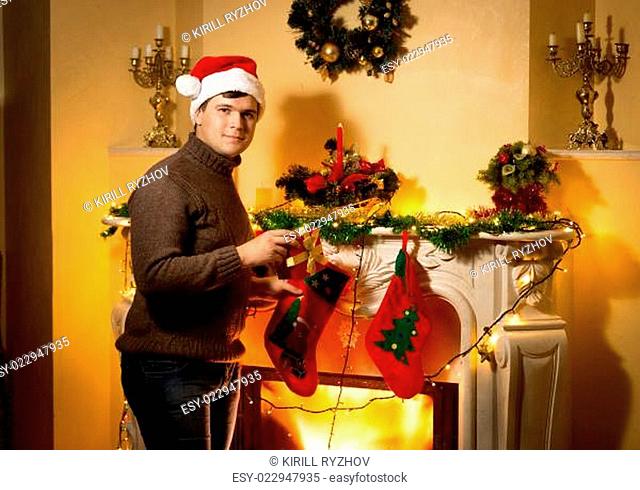 smiling man posing with gift box at decorated fireplace