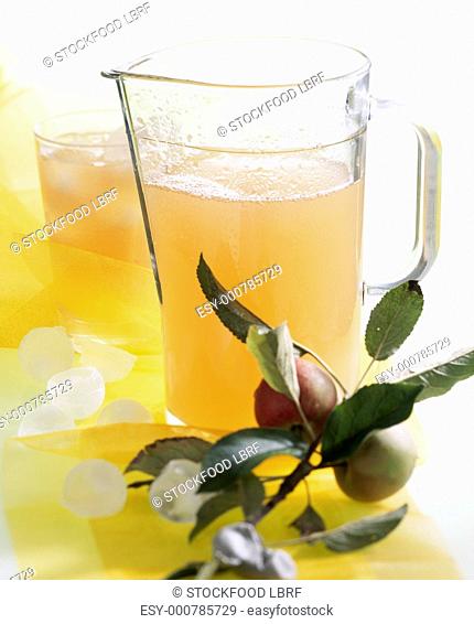 Apple juice in a glass jug and in a glass with ice cubes