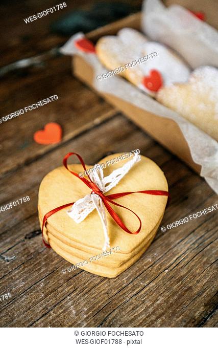 Stack of four heart-shaped shortbreads tied with lace and ribbon on wood