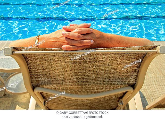 A senior woman in a chair beside a pool